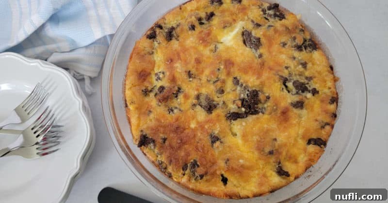 Impossible cheeseburger pie in a glass pie pan next to a stack of white plates and forks