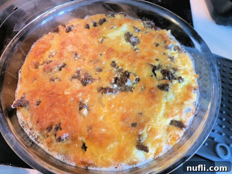 Impossible cheeseburger pie in a glass pie dish on the stovetop after baking