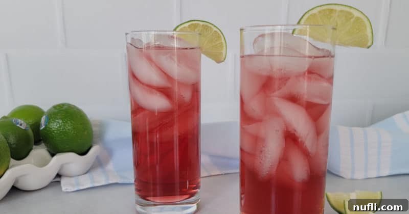 Effortless 3-Ingredient Woo Woo Cocktail 7 Two red woo woo drinks in tall glasses with lime wedges next to a stack of limes