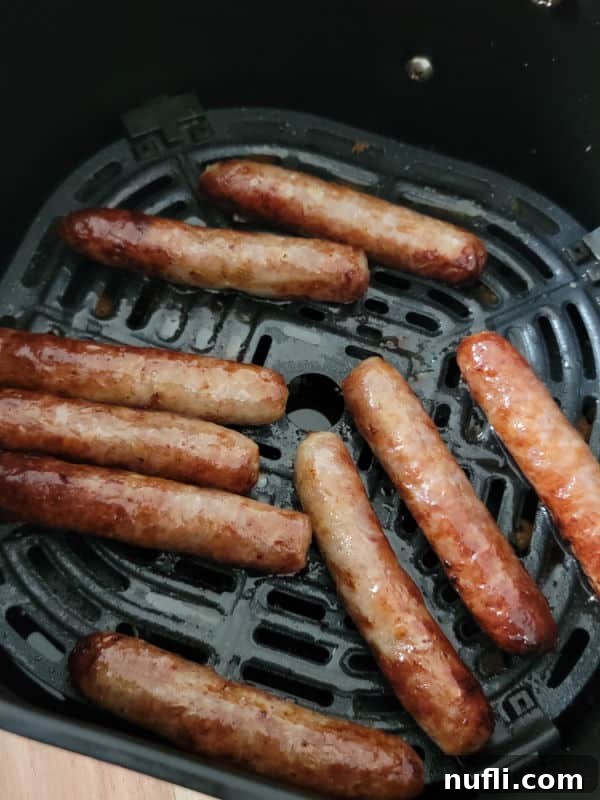 Crispy Air Fryer Sausages 6 A close-up view of a basket filled with freshly cooked, golden-brown air fryer sausage links, steamy and inviting.