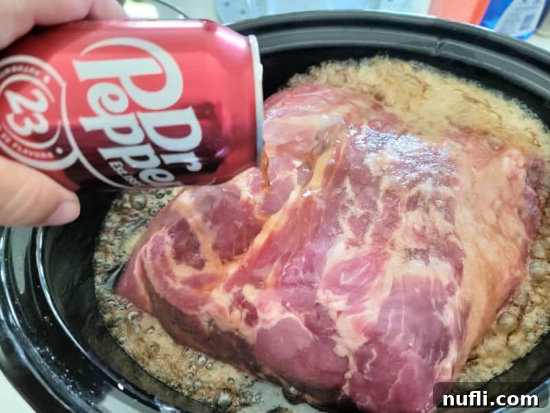 Dr pepper can pouring over a pork but in a slow cooker bowl 