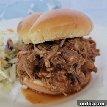 Dr Pepper Pulled pork piled on a sandwich bun next to coleslaw