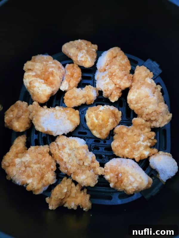 Frozen popcorn chicken in an air fryer basket