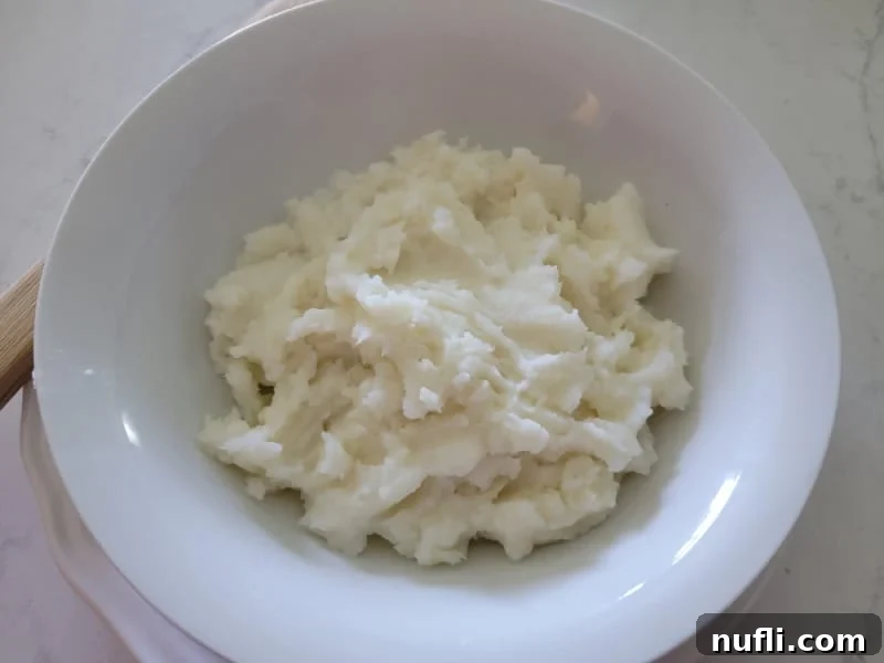 Smooth, creamy mashed potatoes in a white bowl, ready for layering.