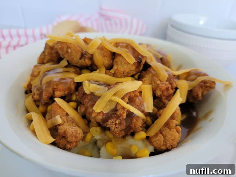 A fully assembled Copycat KFC Famous Bowl, with all layers visible and cheese melted, served in a white bowl.
