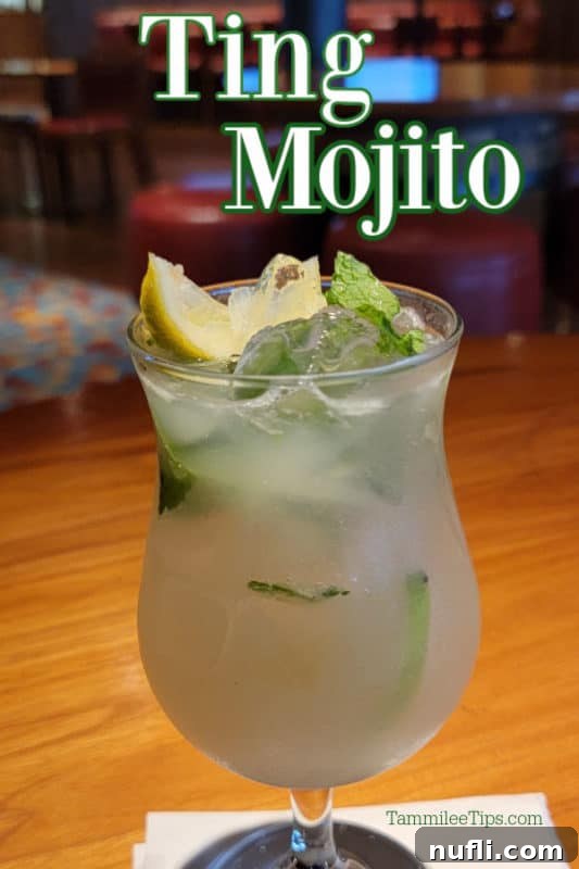 The Ultimate Carnival Cruise Ting Mojito 2 A vibrant Ting Mojito cocktail in a hurricane glass, garnished with fresh mint leaves and a lemon slice.