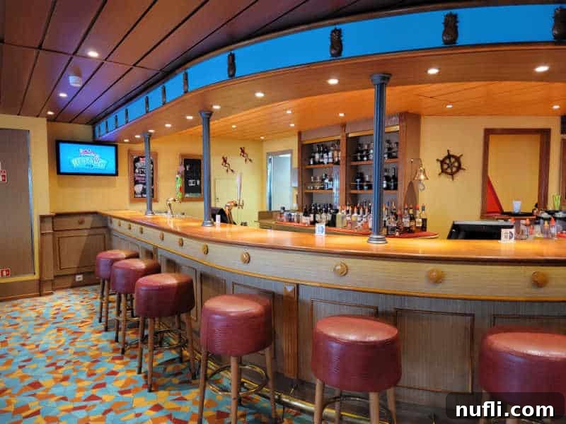 The Ultimate Carnival Cruise Ting Mojito 4 A view of the Red Frog Pub bar on a Carnival Cruise ship, featuring bar stools and a television screen.