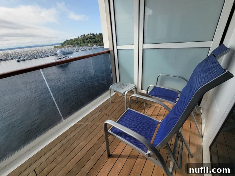 Extended balcony with two chairs and a small metal table looking out over the water with boats in the marina