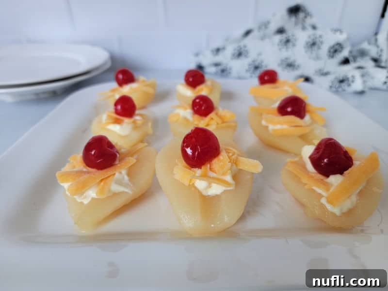 The completed Southern Pear Salad, with rows of pear halves adorned with mayonnaise, cheddar cheese, and maraschino cherries, artfully arranged on a white platter, ready for a gathering.