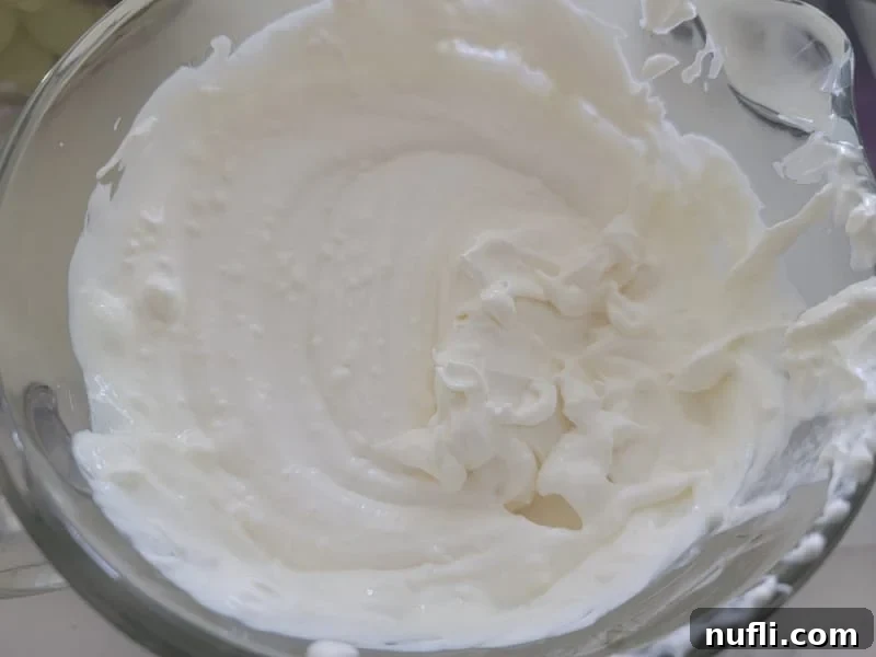 A smooth, creamy mixture of cream cheese, sour cream, sugar, and vanilla extract, perfectly blended in a glass bowl.