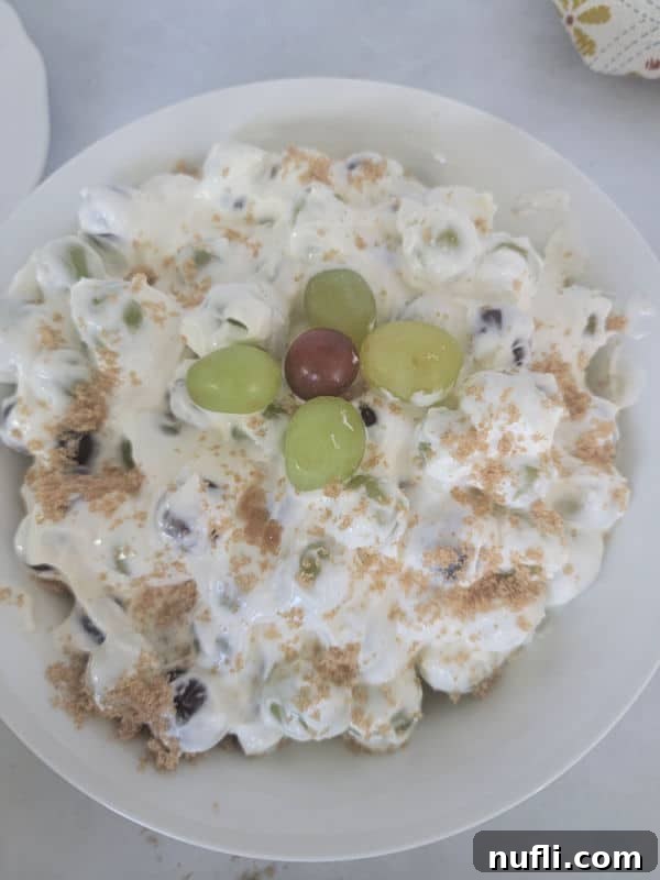 A generous serving of creamy grape salad, beautifully presented in a white bowl, ready to be enjoyed.