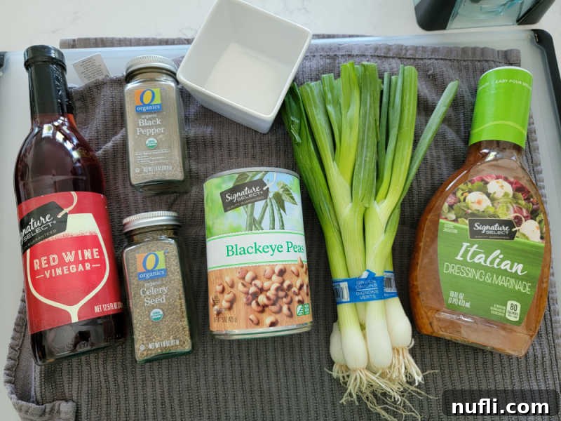 Zesty Black Eyed Pea Medley 3 red wine vinegar, celery seed, black pepper, black eyed peas, green onions and Italian dressing on a grey towel on a cutting board