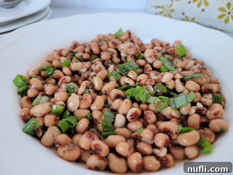 Zesty Black Eyed Pea Medley 7 Black eyed pea salad in a white bowl with a stack of bowls behind it
