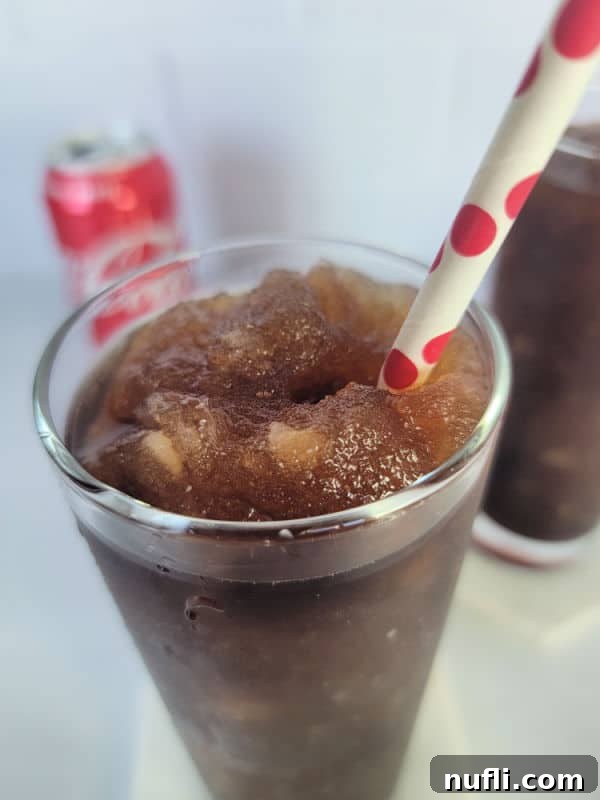 Close up of frozen coke in a tall glass with a red polka dot straw