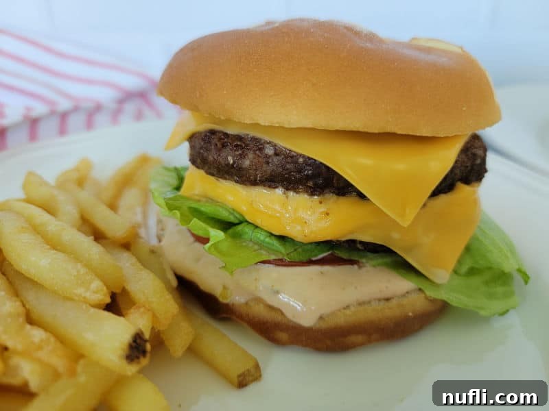 Cheeseburger with in n out sauce next to french fries on a white plate