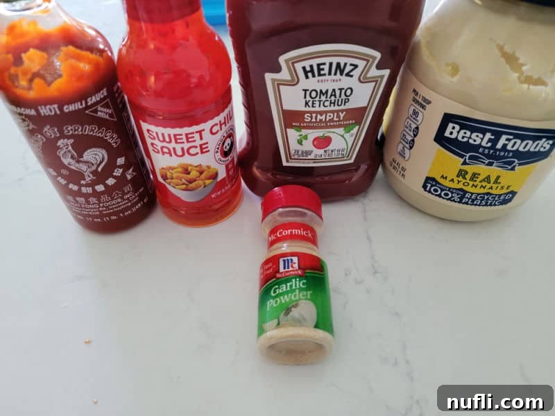 Sriracha, sweet chili sauce, ketchup, mayo, and garlic powder on a white counter 
