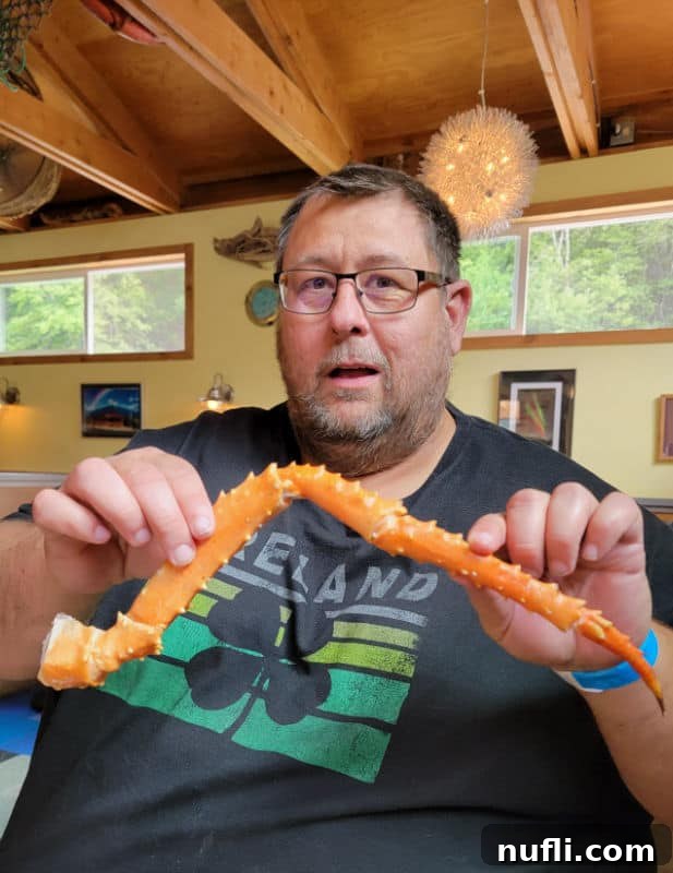John holding a large Alaskan King Crab leg with a look of awe