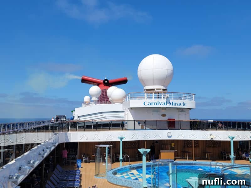 Carnival miracle sign above a pool and Carnival Funnel in the background 