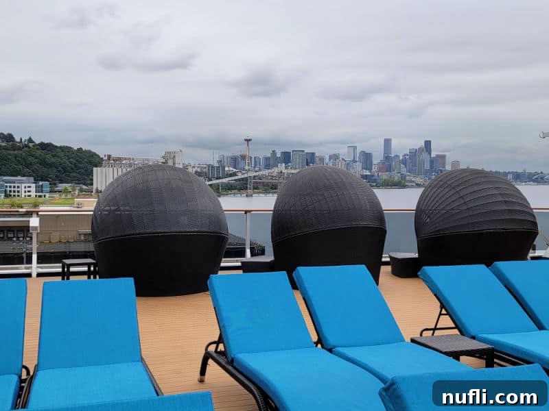 blue deck chairs lined up with the Seattle skyline and Space needle in the distance. 