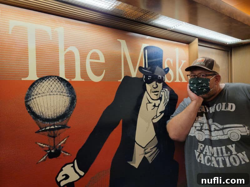 john standing next to a mural of The Mask with a male figure wearing an eye mask and top hat