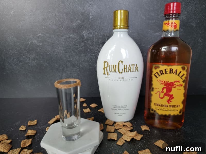 Sweet Cinnamon Crunch Shooter 3 empty shot glass sitting on two marble coasters next to a bottle of Rumhcata and Fireball