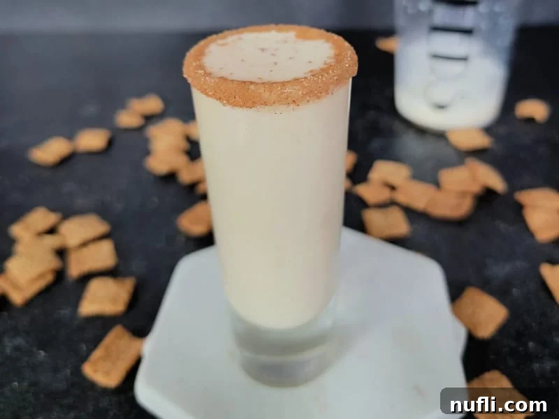 Sweet Cinnamon Crunch Shooter 9 Cinnamon toast crunch shot on a marble coaster with cereal and a cocktail shaker