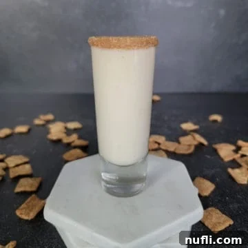 Sweet Cinnamon Crunch Shooter 10 Cinnamon Toast Crunch Shot in a tall shot glass on white coasters surrounded by cereal