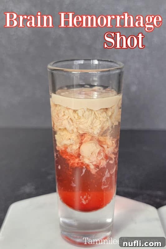 Brain Hemorrhage Shot Video Recipe 2 A vividly unsettling Brain Hemorrhage Shot with layers of creamy white and deep red, served on a pristine white coaster, ready for a Halloween party.