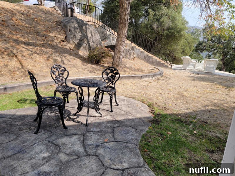 Hounds Tooth Inn in Oakhurst California Closed 8 metal table and chairs on a rock walkway near trees, providing a peaceful outdoor seating area