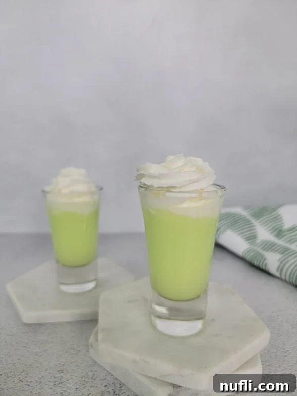 Easy Scooby Snack Shot Recipe 5 creamy green scooby snack shot with whipped cream garnish in a glass shot glass.