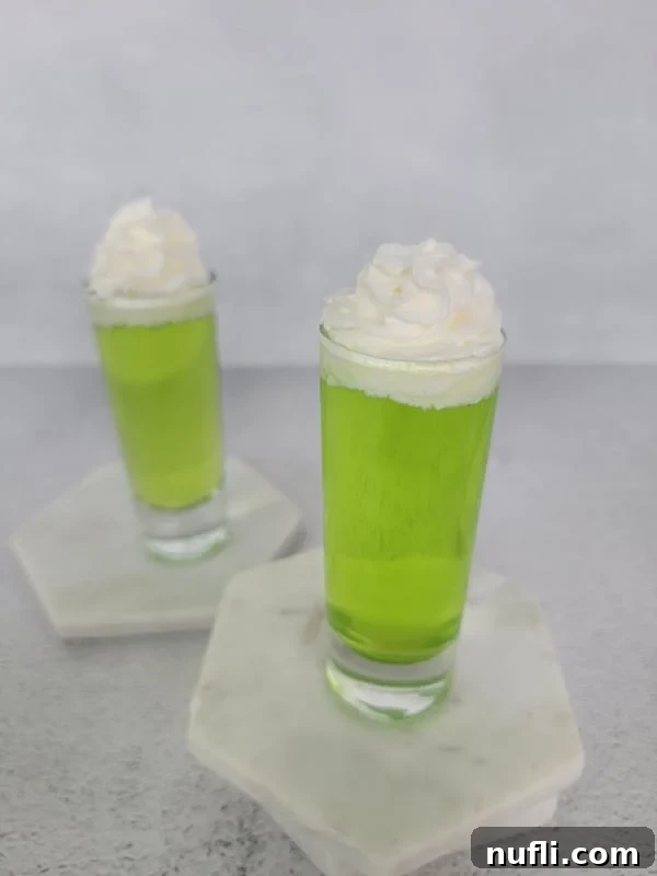 Easy Scooby Snack Shot Recipe 6 Bright Green Scooby Snack Shot in a glass shot glass garnished with whipped cream