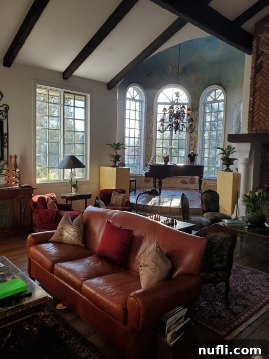 leather couch with pillows near a piano, chandelier, and large picture windows. 