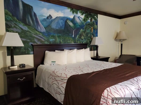 Yosemite mural painted above a bed with pillows and a nightstand with a lamp