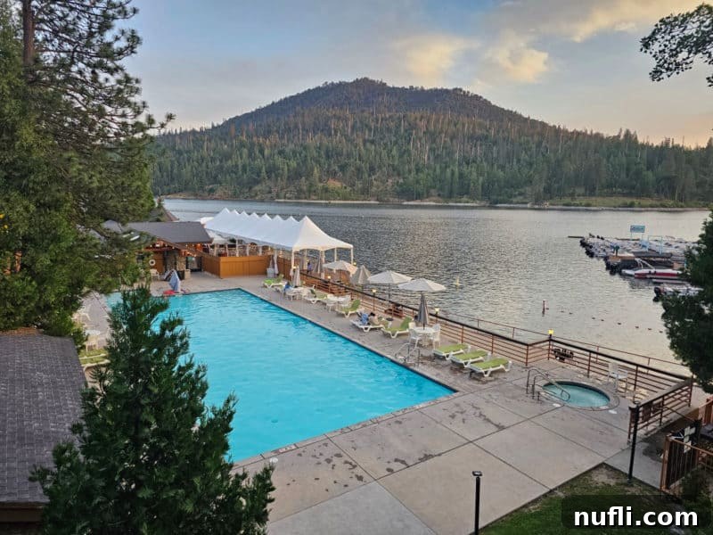 Swimming pool and deck next to a lake with a mountain in the background