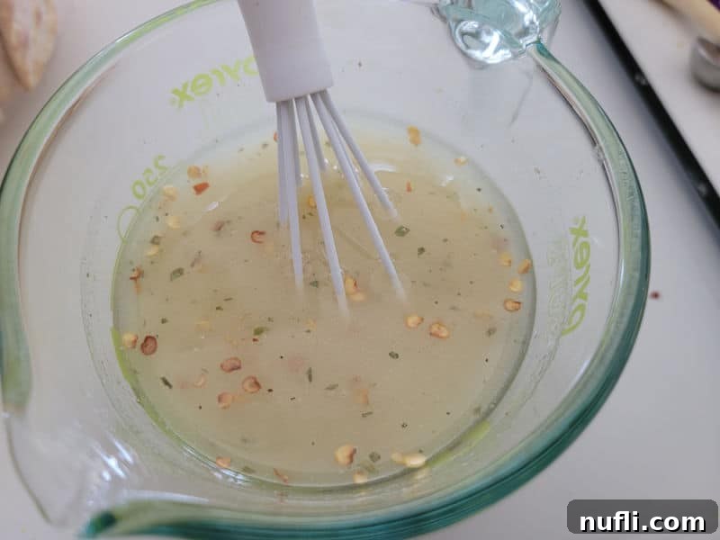 A small bowl containing the Alabama Fire Cracker seasoning mix: oil, red pepper flakes, and dry ranch dressing mix, ready to be stirred.