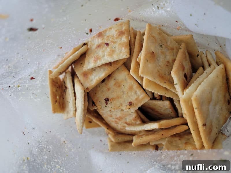 A clear plastic bag filled with Alabama Fire Crackers, showing the seasoning evenly distributed on the surface of the crackers after shaking.