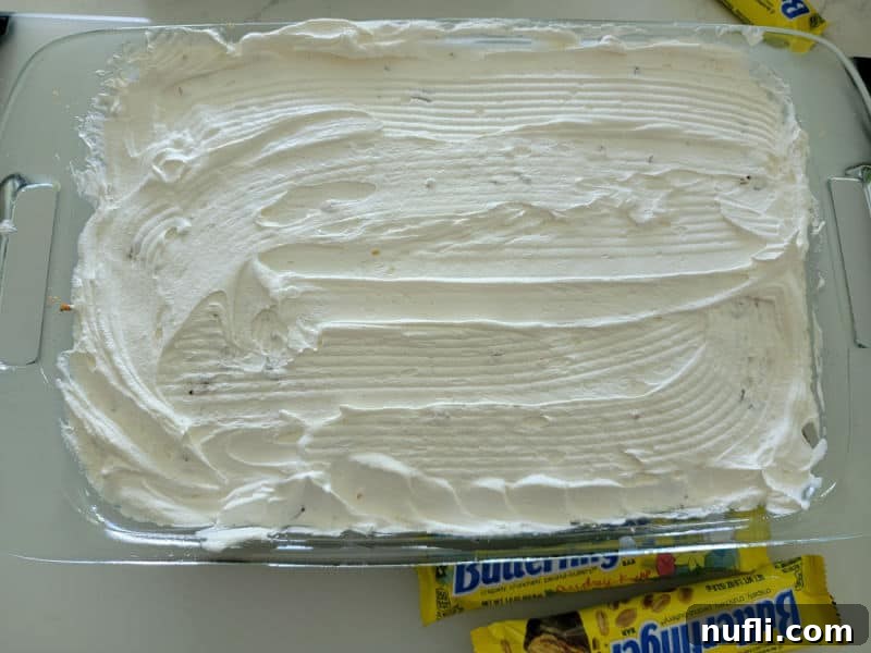 Cool whip spread over a chocolate poke cake for Butterfinger cake