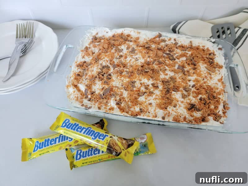 Butterfinger cake in a large dish next to Butterfinger candy bars
