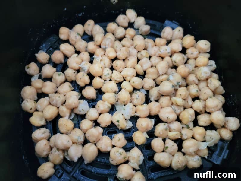 Seasoned chickpeas in an air fryer basket, ready for cooking