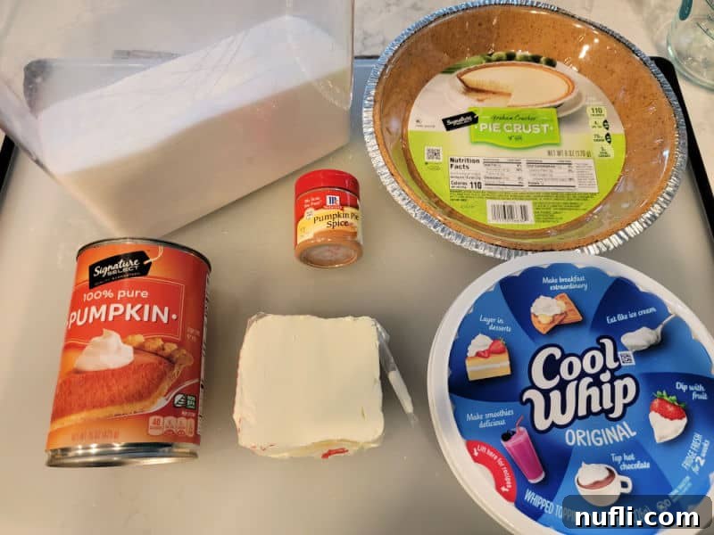sugar, pumpkin in a can, cream cheese, pumpkin pie spice, graham cracker crust, and cool whip on a counter
