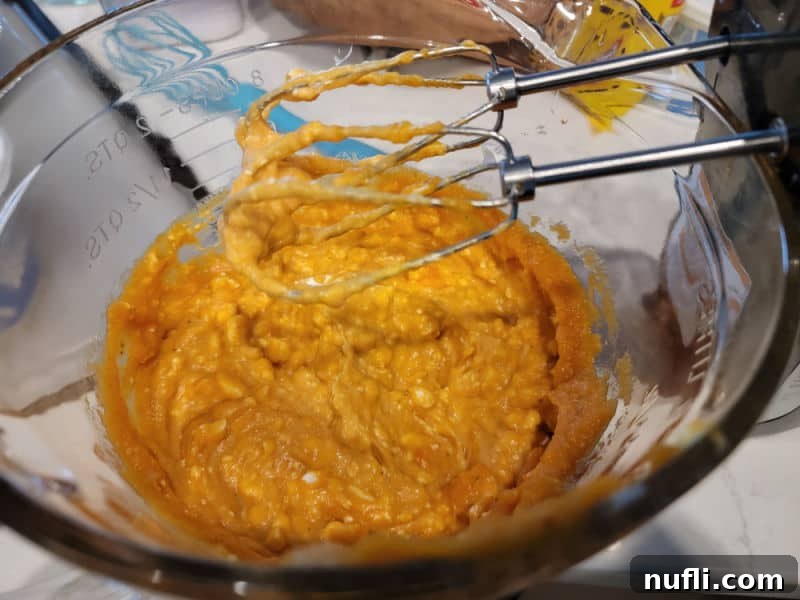 mixer beaters over a glass bowl with pumpkin in it