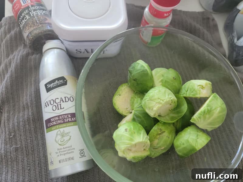bowl of Brussel sprouts next to avocado oil, salt, pepper, and garlic powder