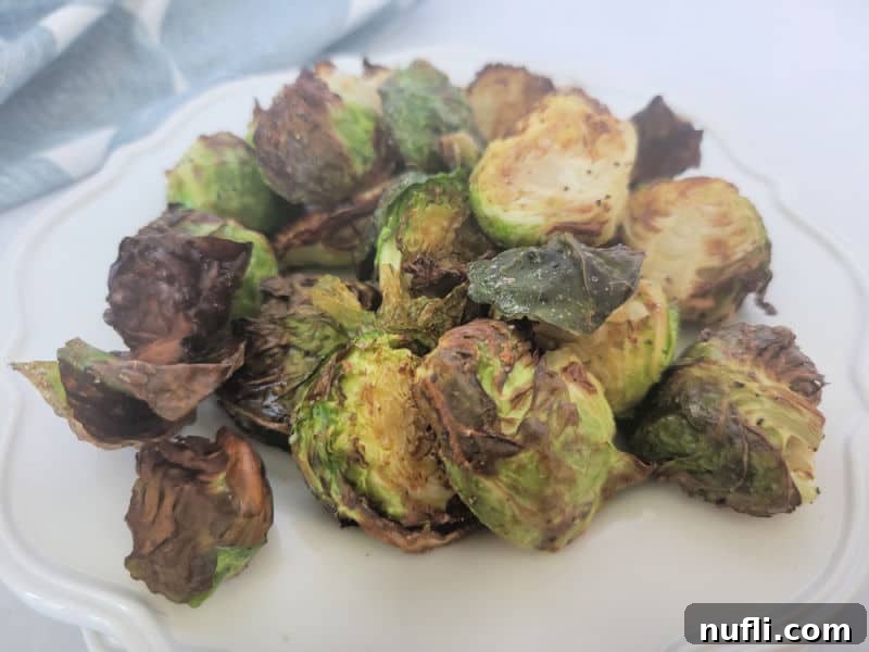 Air fried Brussel sprouts piled on a white plate near a napkin