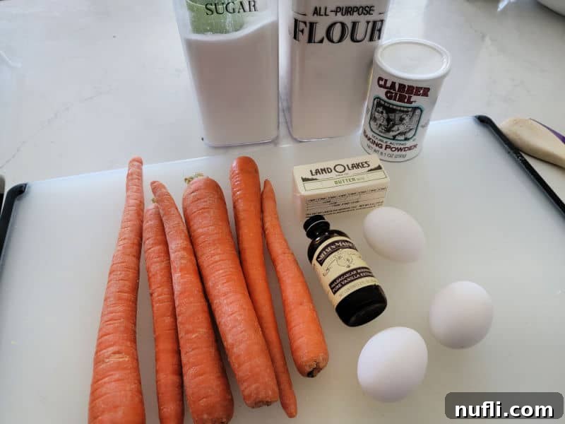 Easy Fluffy Carrot Soufflé 3 Carrot souffle ingredients laid out: fresh carrots, unsalted butter, granulated sugar, all-purpose flour, baking powder, vanilla extract, and eggs