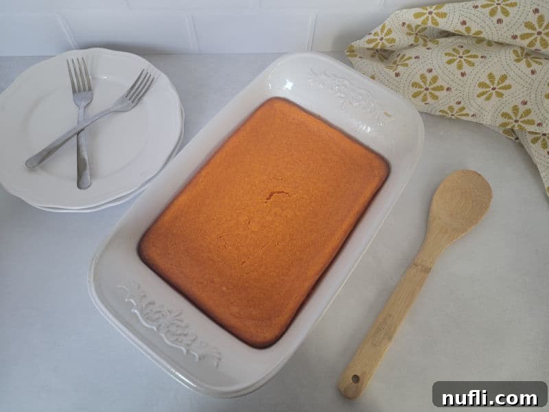 Easy Fluffy Carrot Soufflé 7 Baked carrot soufflé in a casserole dish, golden brown and perfectly set, with a wooden serving spoon and plates nearby