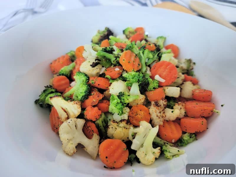 Air fryer mixed frozen vegetables on a white plate with carrots, cauliflower, and broccoli, perfectly cooked.