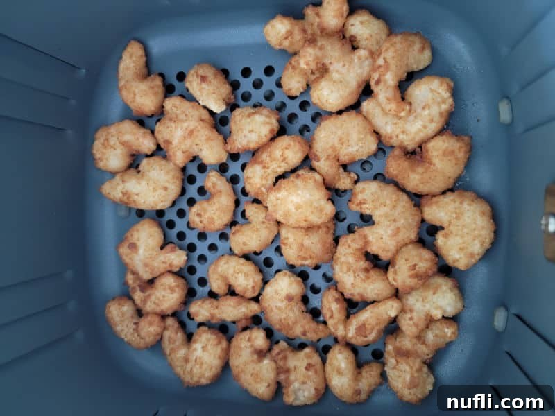 Crispy Air Fryer Frozen Popcorn Shrimp 4 Frozen popcorn shrimp spread in a single layer in an air fryer basket