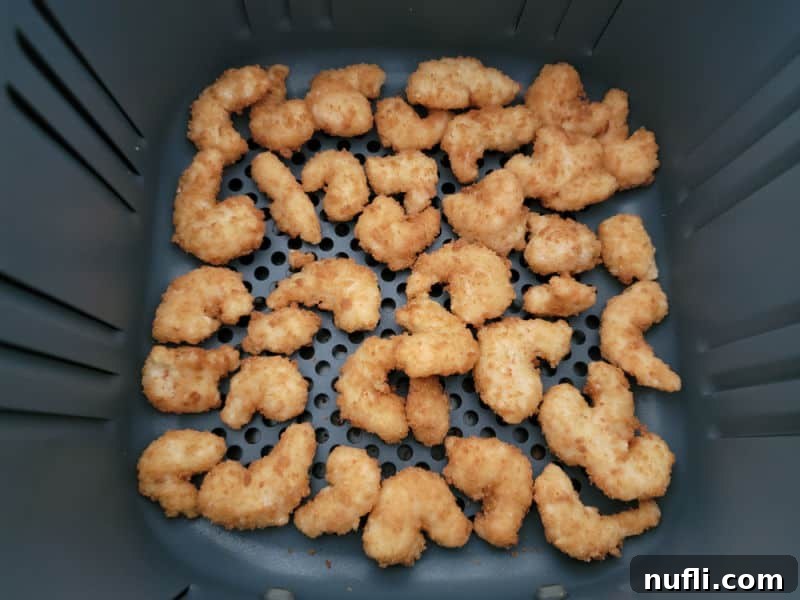 Crispy Air Fryer Frozen Popcorn Shrimp 5 Air fried, golden brown shrimp in an air fryer basket after cooking
