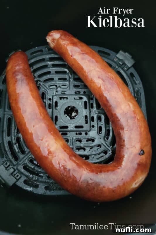 Air fried Kielbasa in an air fryer basket, perfectly golden brown and crispy.