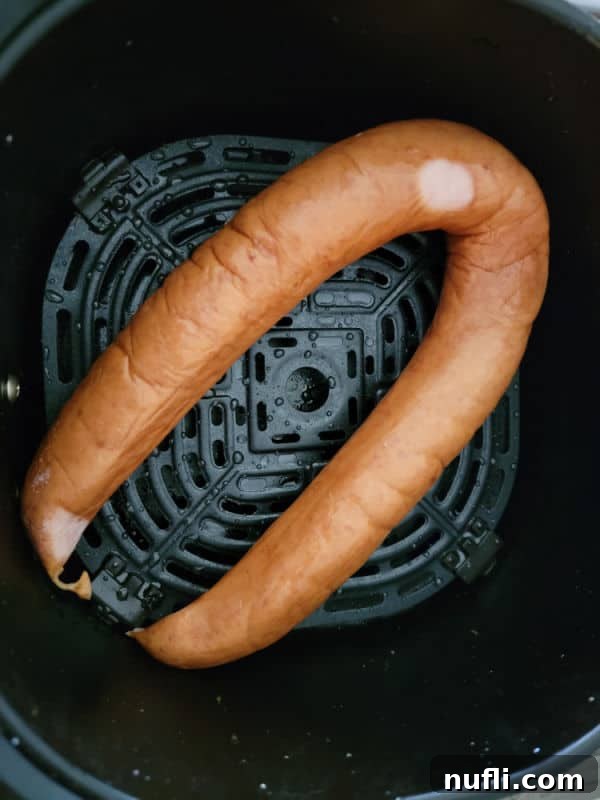 Sliced kielbasa arranged in a single layer in an air fryer basket, ready for air frying.